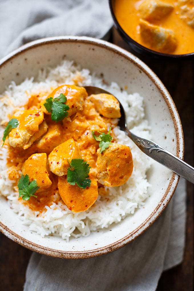 Eine Schüssel mit Hähnchen-Curry mit Kokosmilch und Reis und eine Schüssel gefüllt mit Hähnchen-Curry.