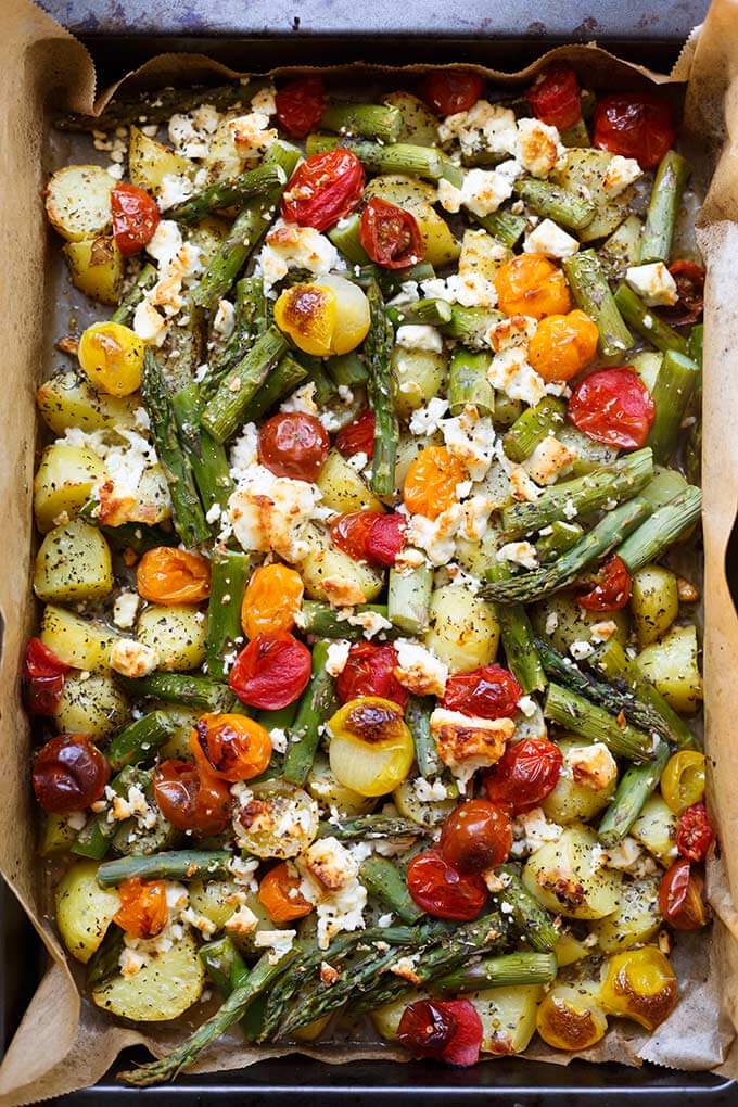 Ofenkartoffeln mit grünem Spargel, Tomaten und Feta auf einem Backblech