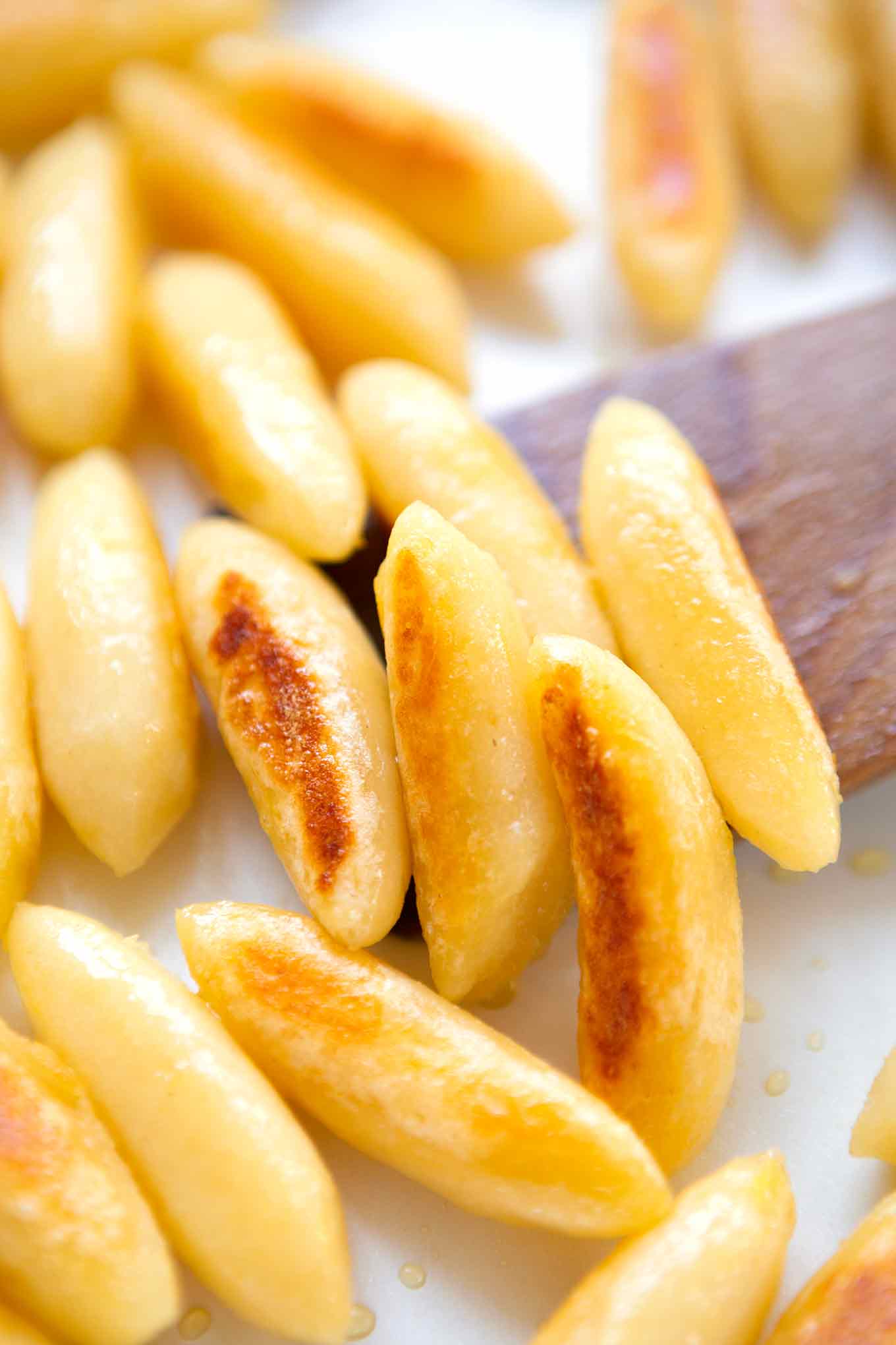 Nahaufnahme der gebratenen Gnocchis für die Lauch-Schupfnudel-Pfanne mit einem Holzlöffel in einer weißen Pfanne