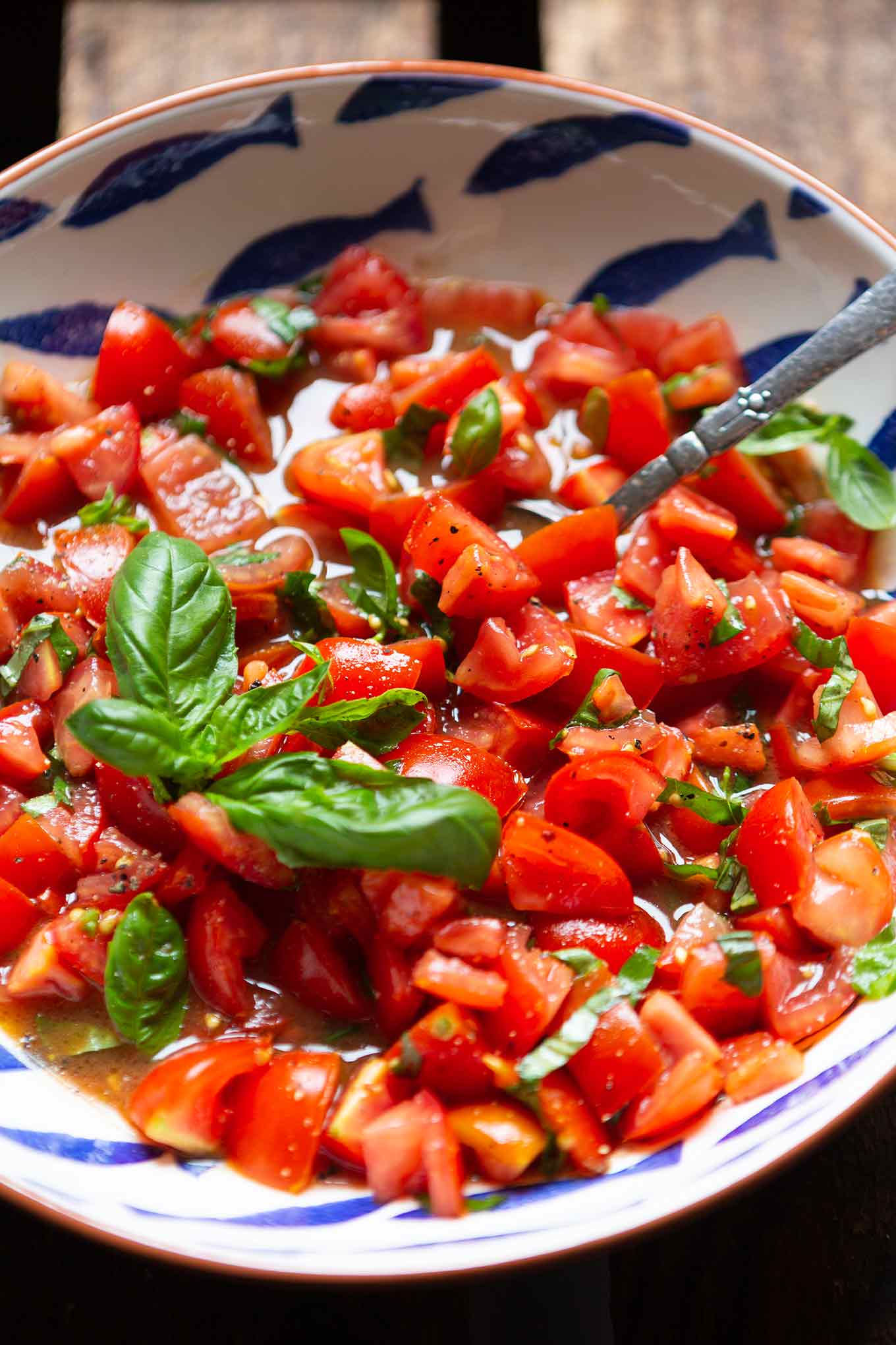 Der einfache Tomatensalat in einer Schüssel mit einer Gabel. Garniert mit Basilikum.