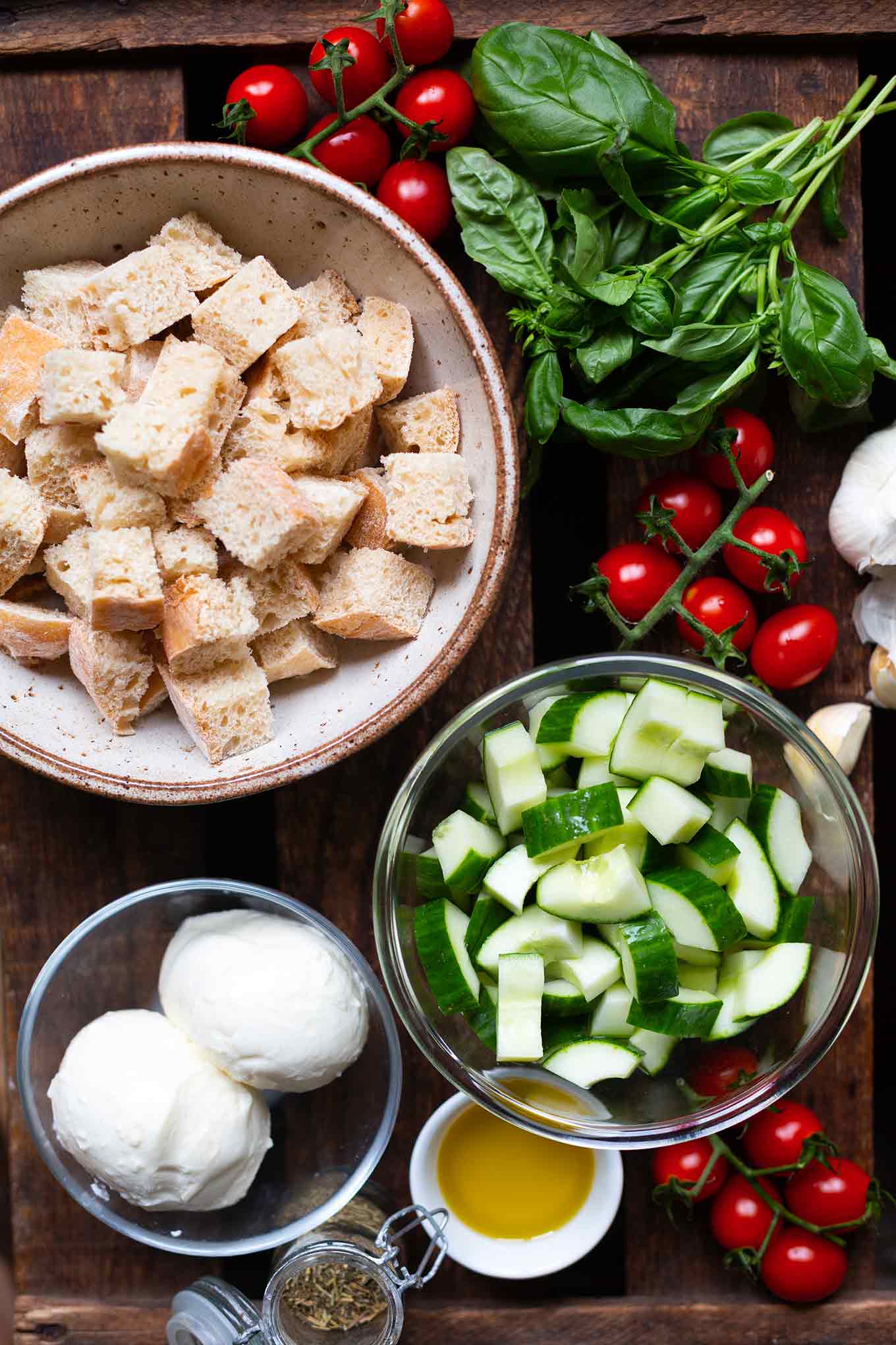 Die Zutaten für Brotsalat - Ciabatta, Tomaten, Basilikum, Gurke, Mozzarella, Olivenöl und Knoblauch - Kochkarussell