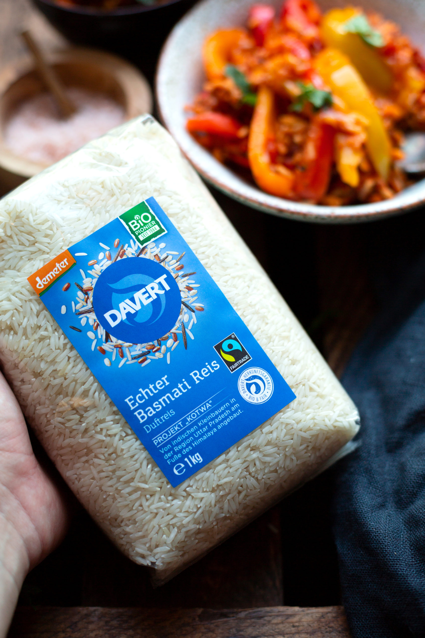 Werbung. Produktfotografie Davert Basmatireis. Im Hintergrund eine vegetarische Paprika-Reispfanne mit Hackfleisch in hellen Schüsseln.