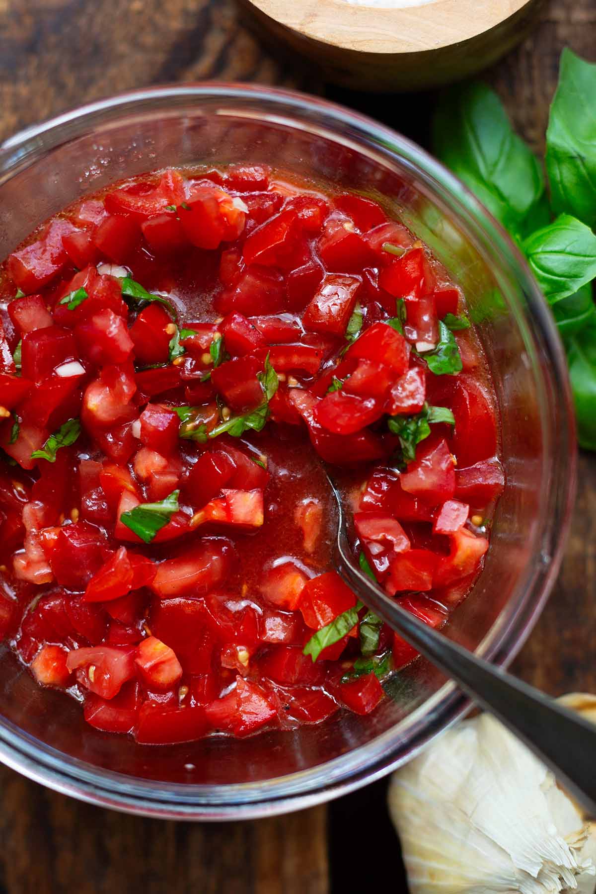 Zerschnitte Tomaten als Belag für die Bruschetta in einer Glasschüssel. Mit dem Basilikum, Olivenölm Knoblauch und Gewürzen abgeschmeckt.
