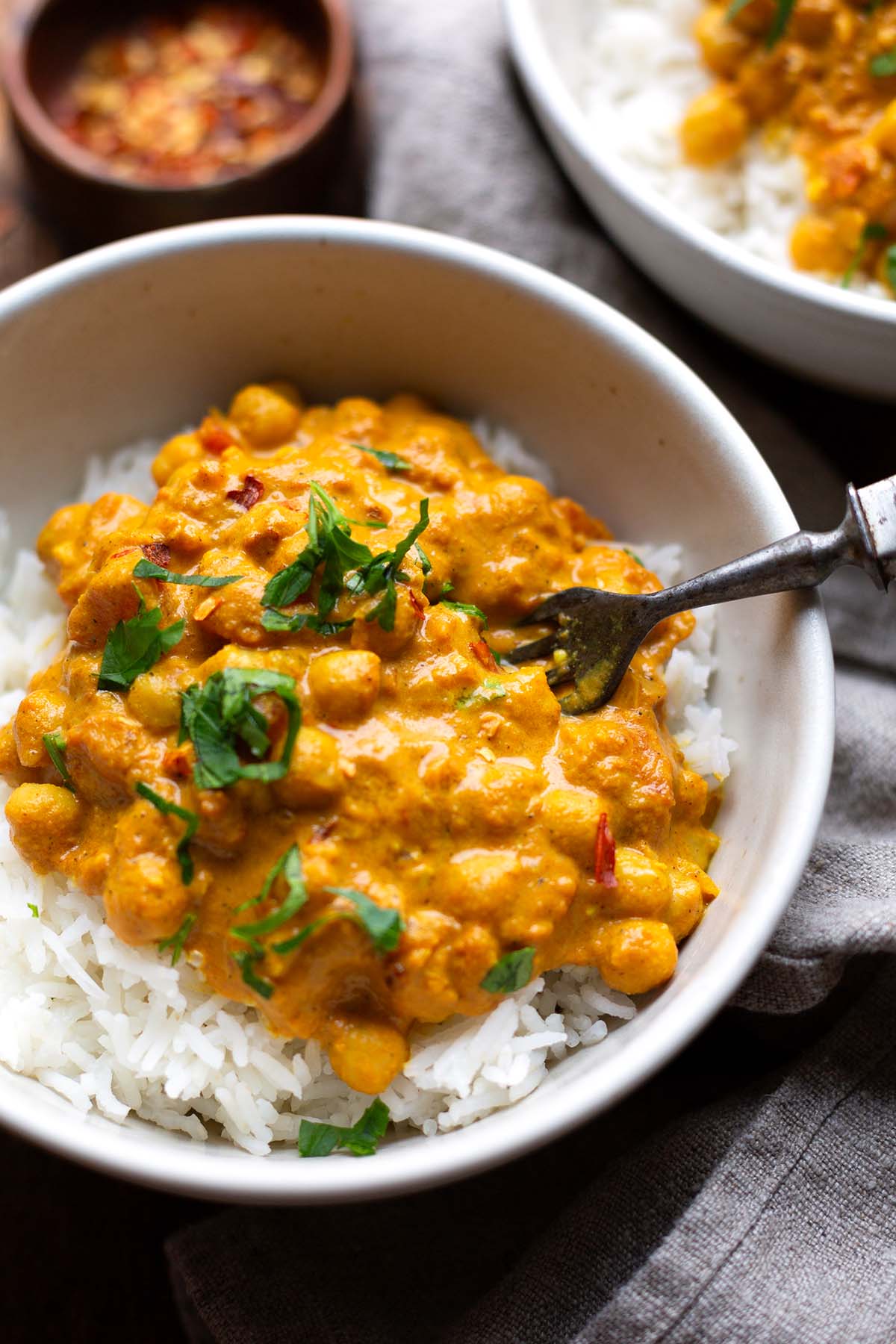 Kichererbsen-Curry mit Kokosmilch, serviert in einer Schüssel mit Reis und Chili