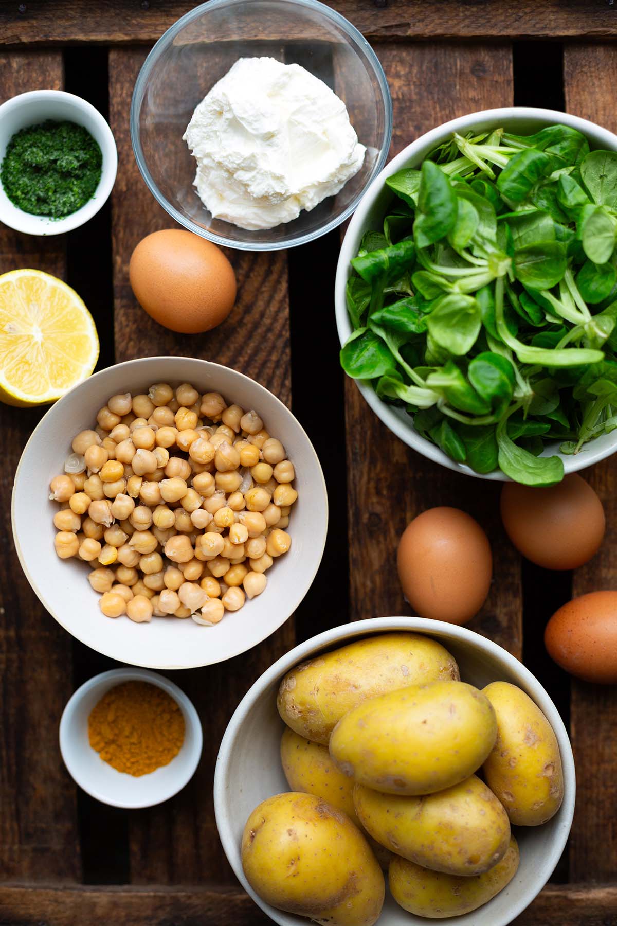 Zutaten für die gesunde Salat Bowl. Zu sehen sind: Kichererbsen, Kartoffel, Magerquark, Eier, Zitrone, Dill und Feldsalat.