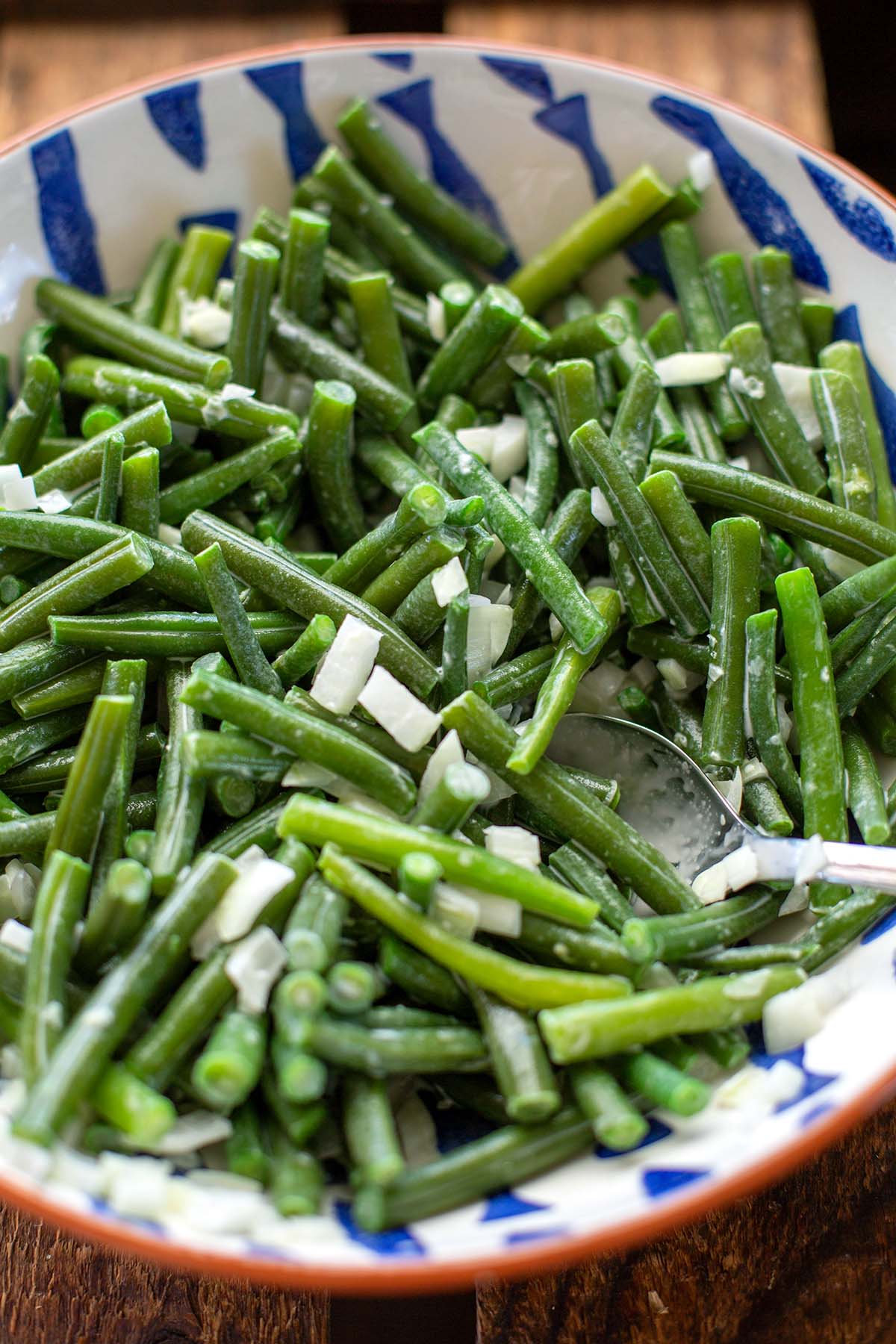 Nahaufnahme vom fertigen Nudelsalat in einer weiß-blauen Schüssel. Ein Löffel ist an der Seite zu sehen.