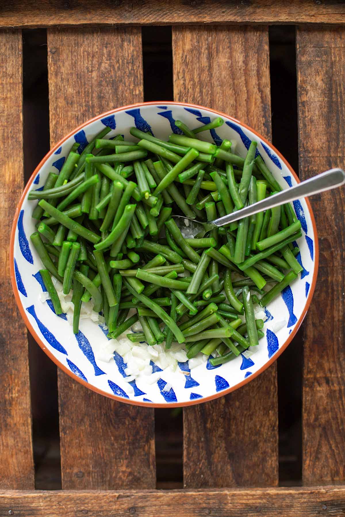 Zutaten für den Bohnensalat mit grünen Bohnen in einer weißen-blauen Schüssel - noch nicht vermischt.