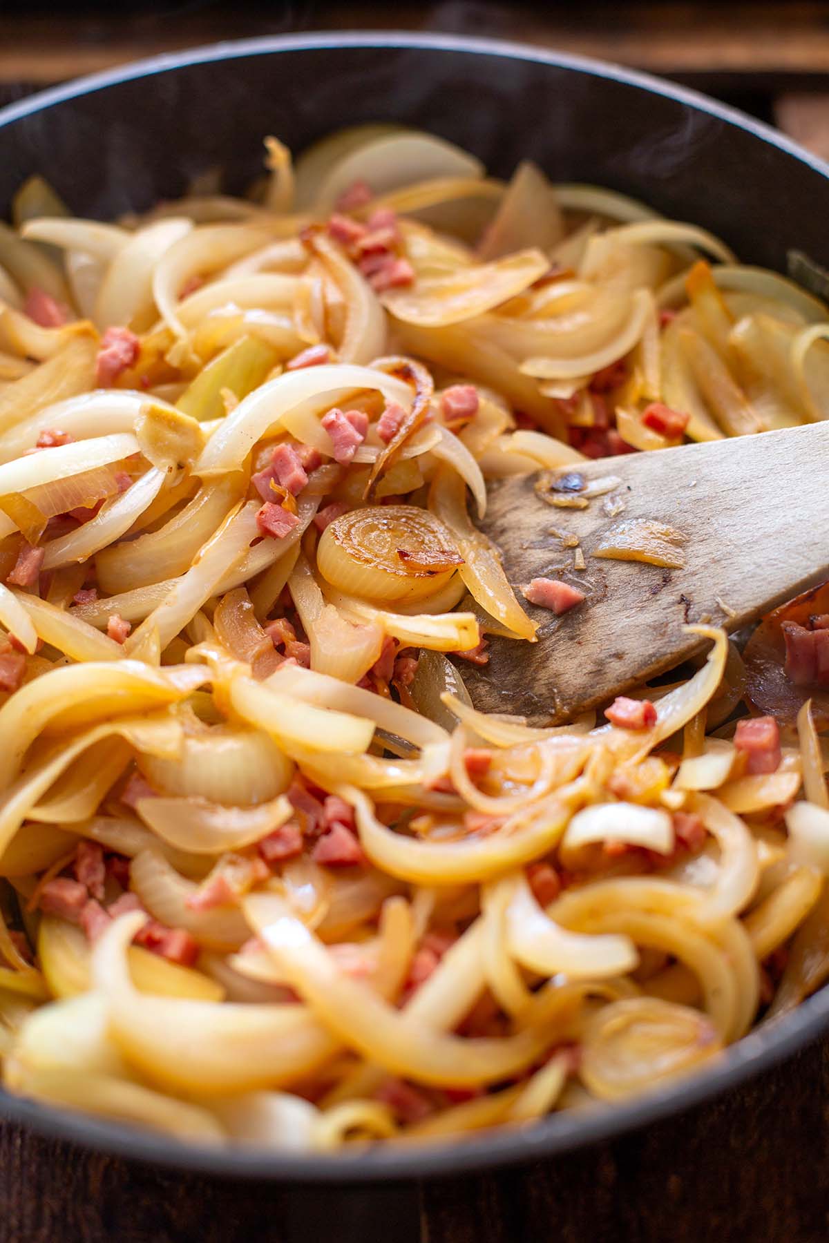 Gedünstete Zwiebeln und Speckwürfel in einer Pfanne