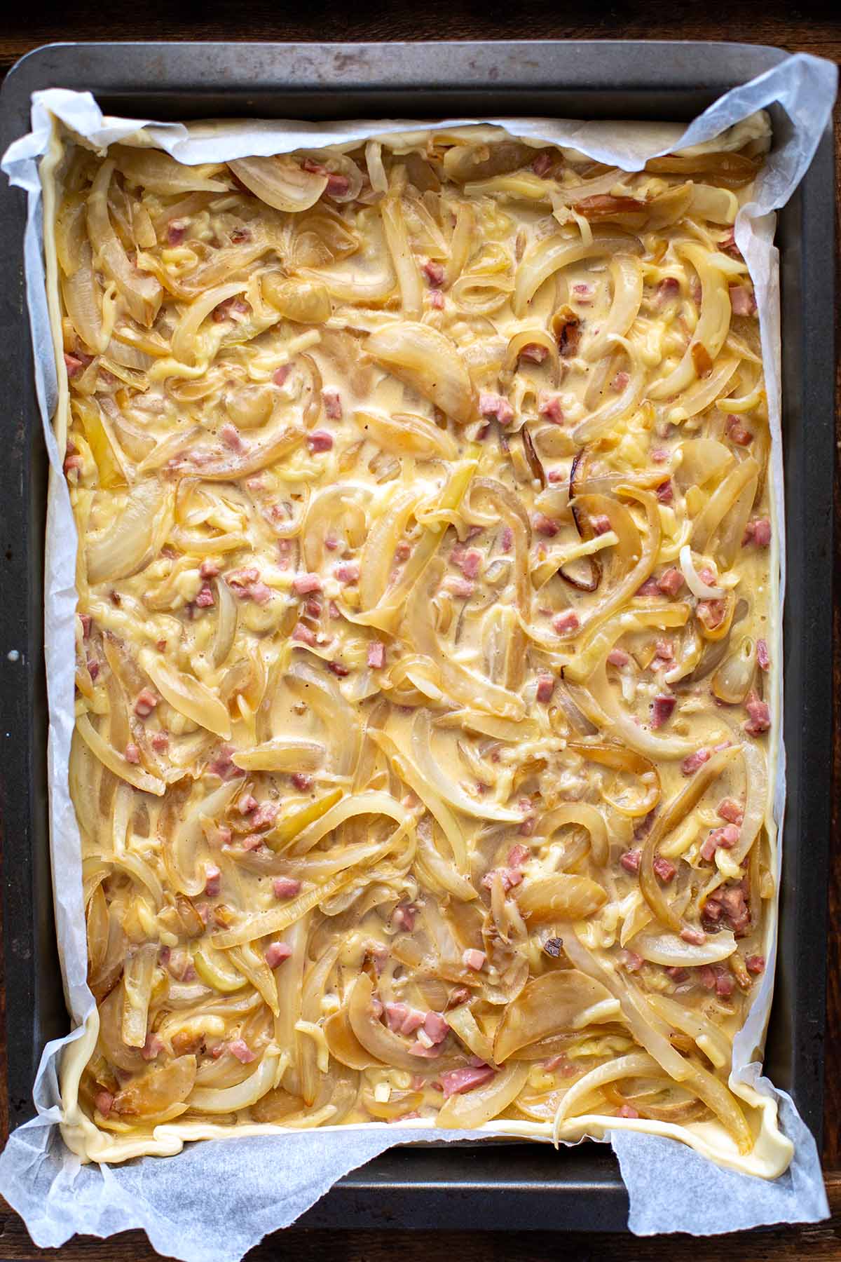 Zwiebelkuchen auf einem Blech vor dem Backen