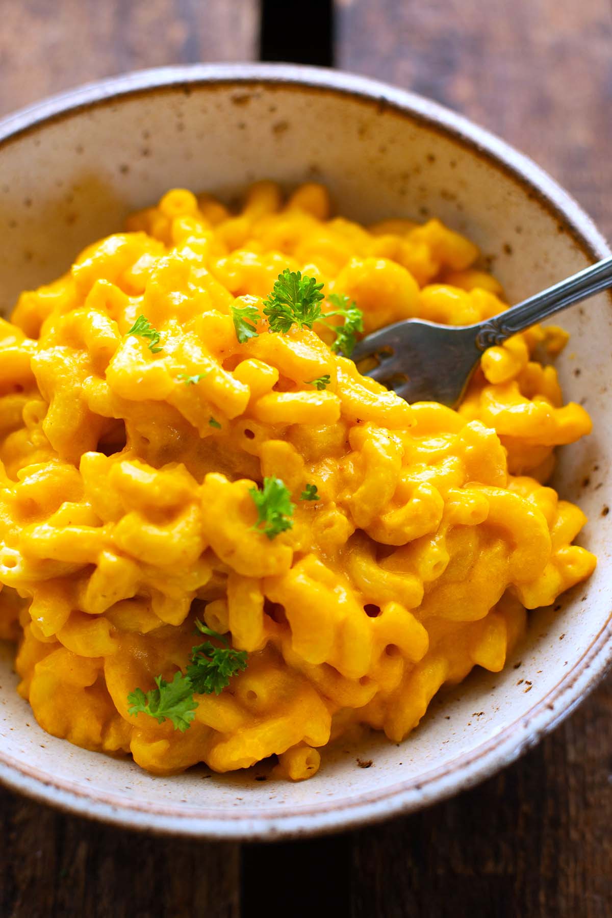 Kürbis Mac and Cheese in einer Schüssel mit Gabel und Petersilie bestreut