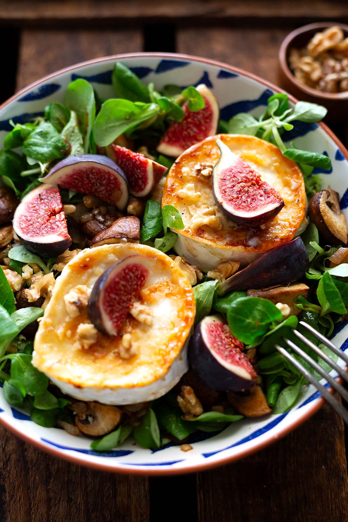 Nahaufnahme vom fertigen Salat mit Ziegenkäse. Zu sehen sind Feldsalat, Feigen, Walnüsse, Champignons, Ziegenkäse.