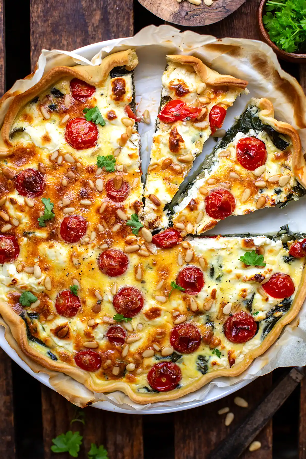 Fertige Mangold Quiche in einer Quiche-Form. Die Quiche ist angeschnitten und zwei Stücke liegen bereit zum Servieren.