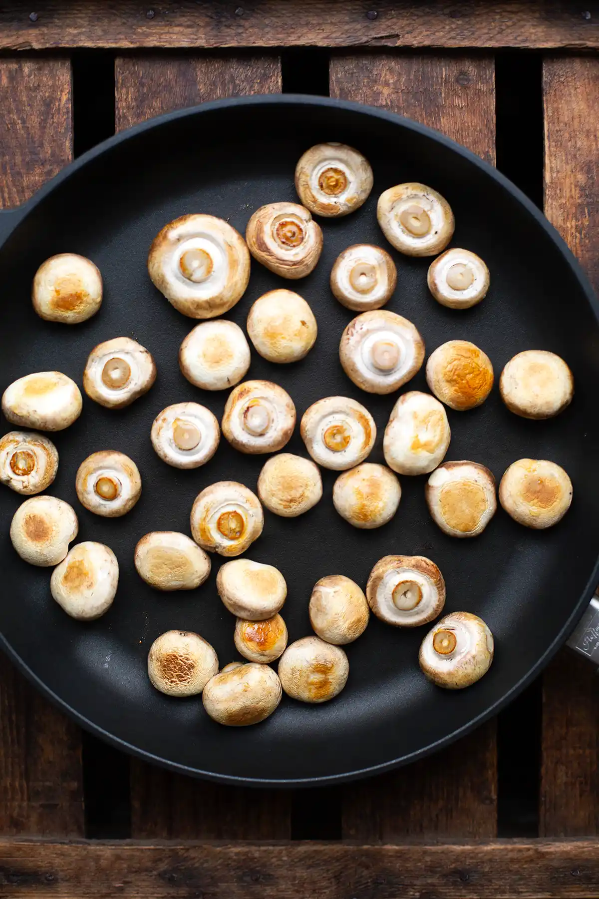 Die weißen Champignons angebraten in einer großen Schmorpfanne.