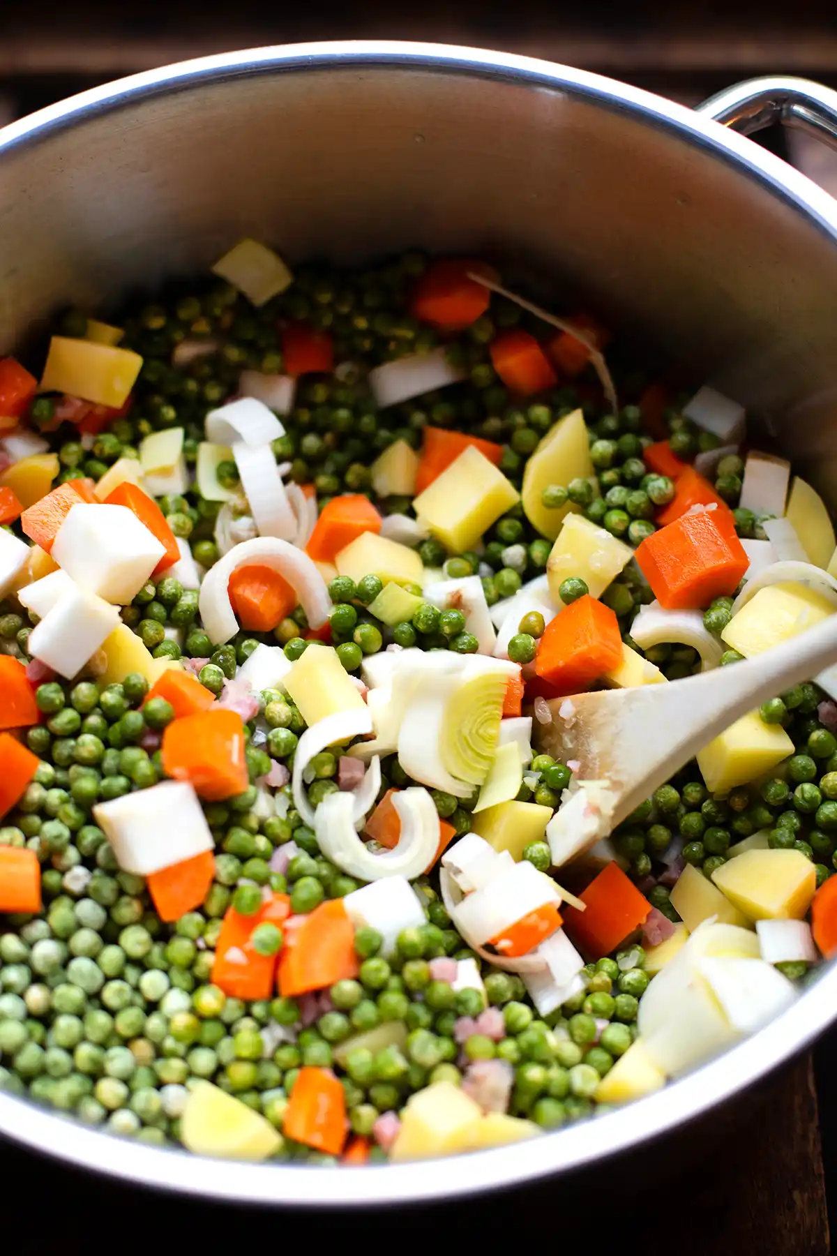 Erbseneintopf wie bei Oma in der Zubereitung. Zu sehen ist ein Topf mit Schälerbsen, Gemüse, Zwiebeln und Schinkenwürfeln