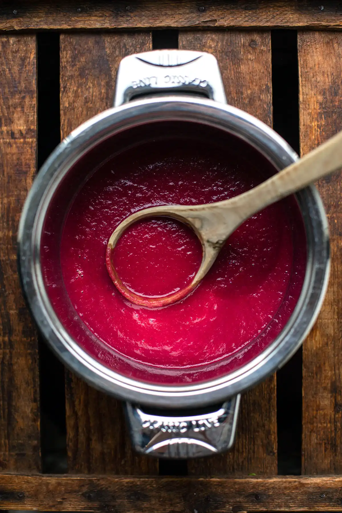 Pürierte Rote-Bete-Suppe in einem Kopftopf mit einem Holzlöffel auf einer rustikalen Holzfläche