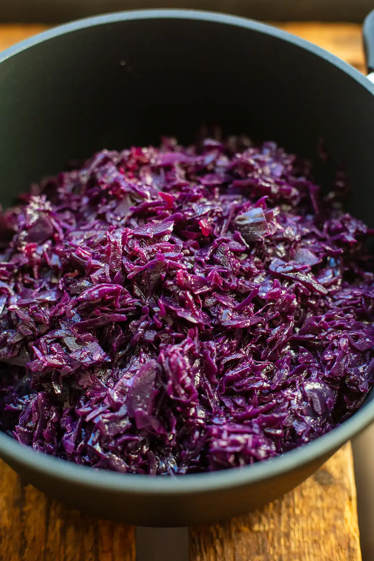 Klassisches Blaukraut köchelt mit Lorbeerblättern in einem dunklen Topf.