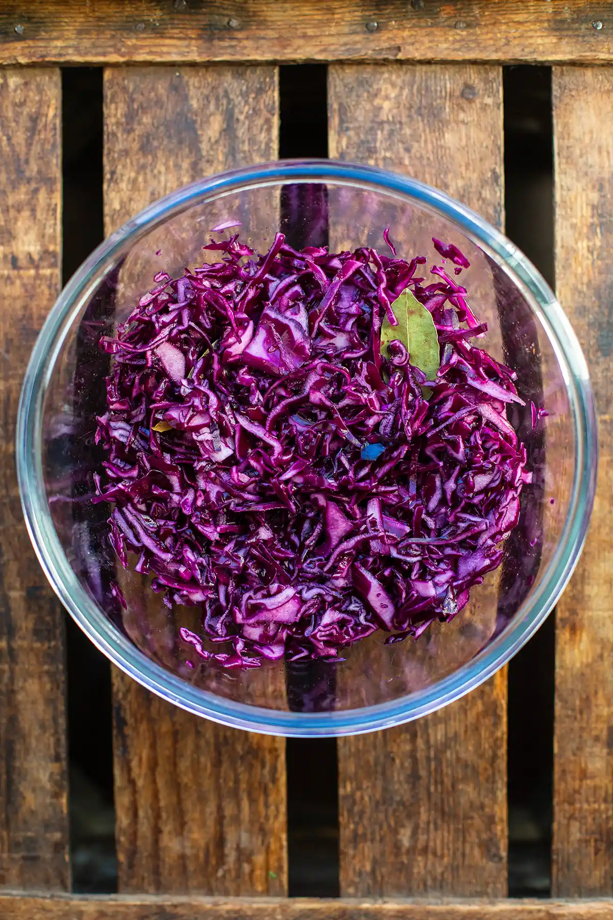 Gehobelter Rotkohl wird in einer Schüssel mit Rotwein und Gewürzen geknetet.