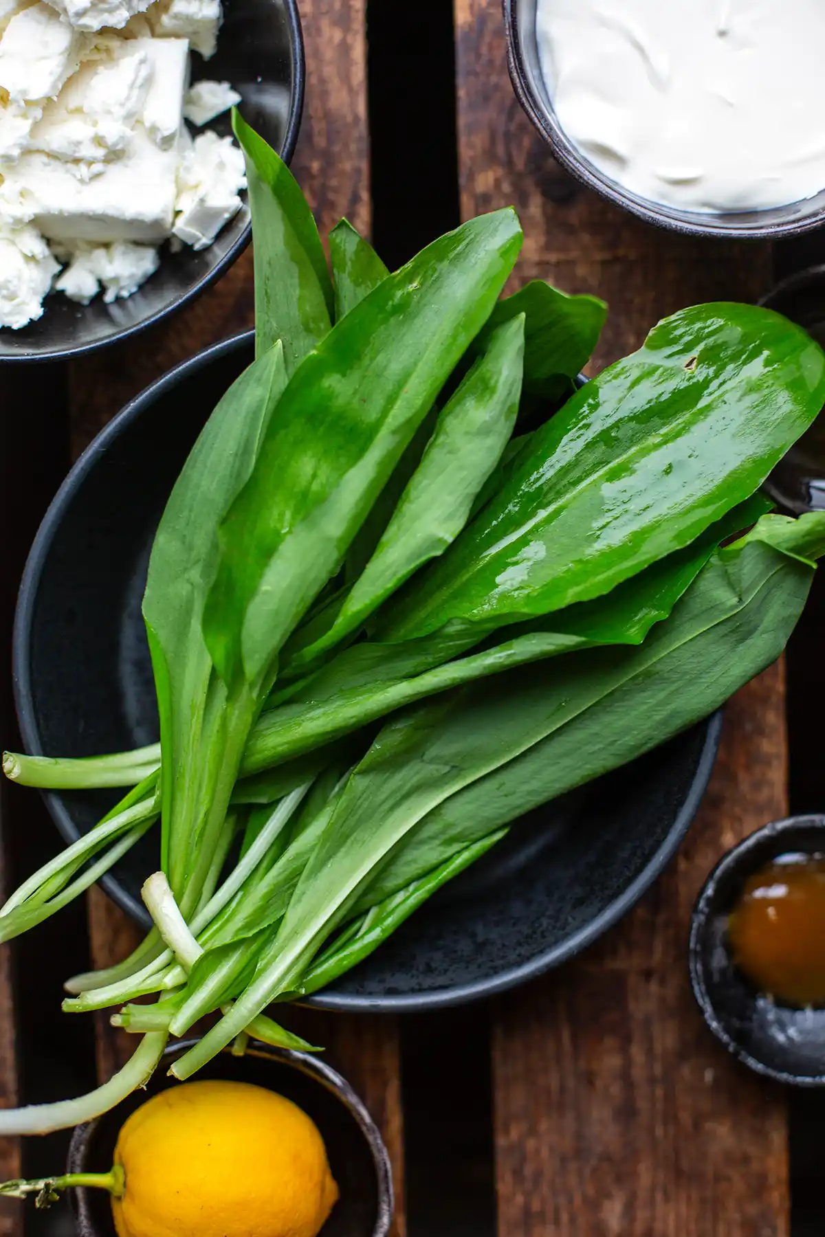 Zutaten für schnellen Bärlauch-Dip: Frischer Bärlauch, Feta, Frischkäse, Zitrone und Honig.