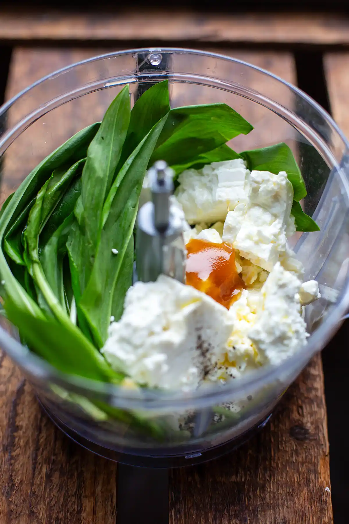 Frischer Bärlauch wird mit Feta und Frischkäse in einem Mixer für einen Bärlauchaufstrich püriert.
