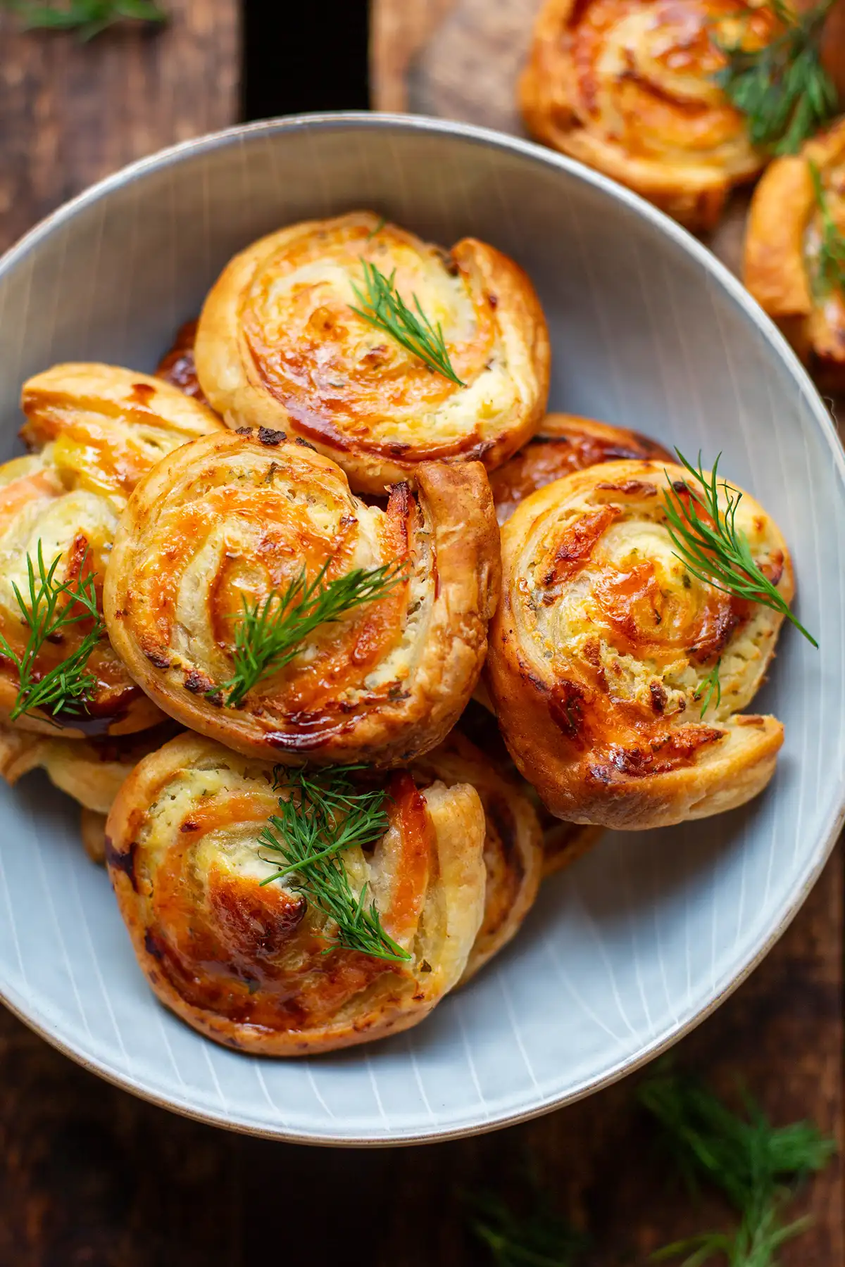 Fertig gebackene Blätterteigschnecken mit Lachs hübsch auf einem Teller angerichtet als Fingerfood.