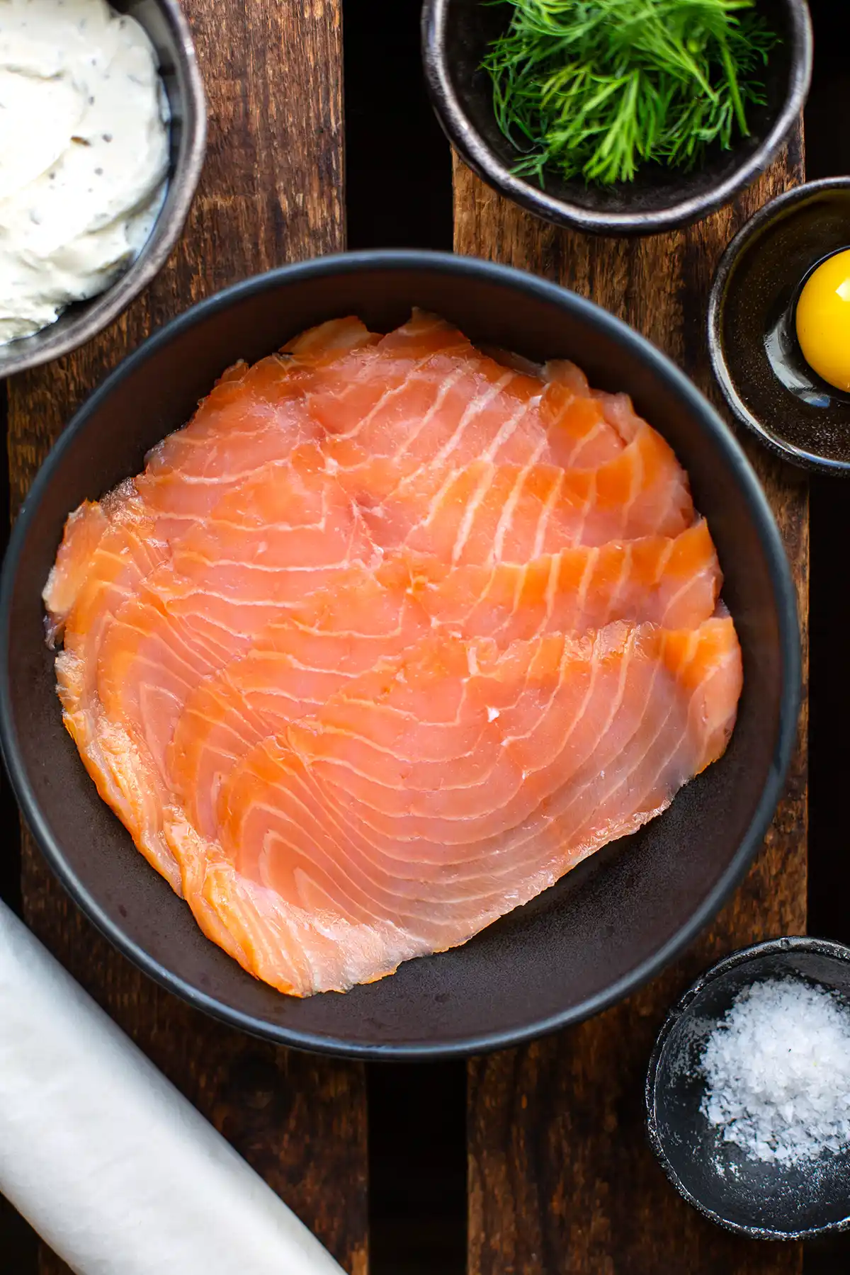 Zutaten für das Rezept Blätterteigschnecken mit Lachs auf einen Blick: Räucherlachs, Blätterteig aus dem Kühlregal, Kräuterfrischkäse und ein Eigelb, dazu Dill für die Deko.