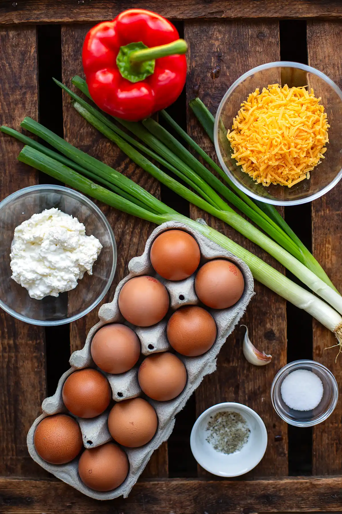 Zutaten für Eiermuffins: Eier, Hüttenkäse. geriebener Cheddar, Paprika, Frühlingszwiebeln, Knoblauch, Salz und Pfeffer.