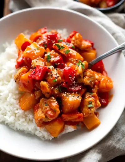 Hähnchen süß-sauer wie beim Chinesen Rezept Fertiges Hähnchen süß-sauer angerichtet auf einem weißen Teller mit Reis.