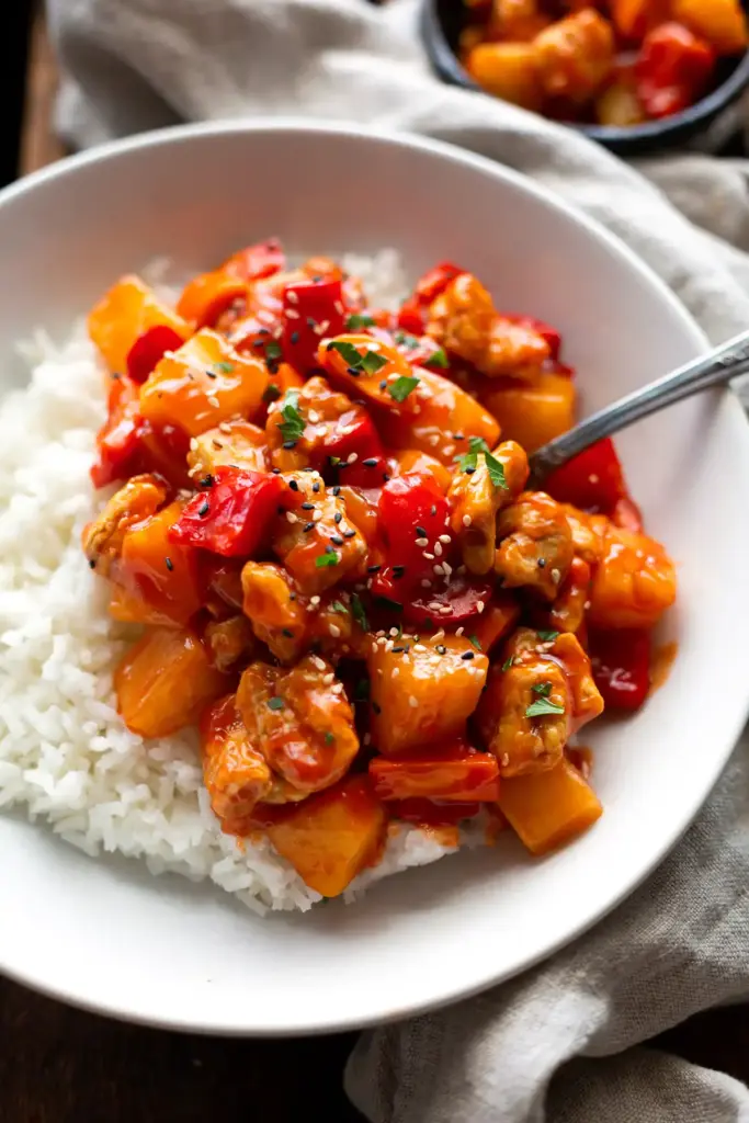 Hähnchen süß-sauer wie beim Chinesen Rezept Fertiges Hähnchen süß-sauer angerichtet auf einem weißen Teller mit Reis.