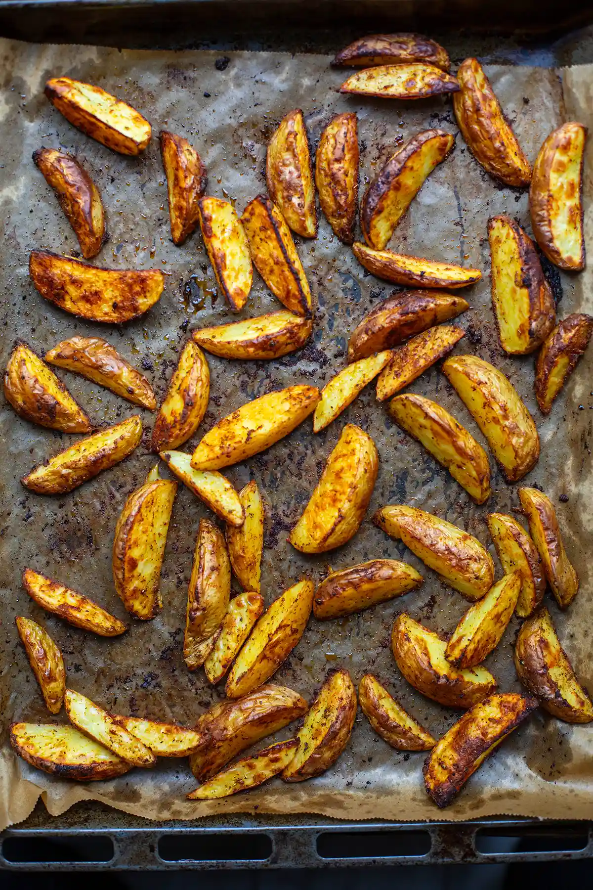 Die Kartoffelspalten fertig gebacken auf Bac kpapier auf dem Backblech.