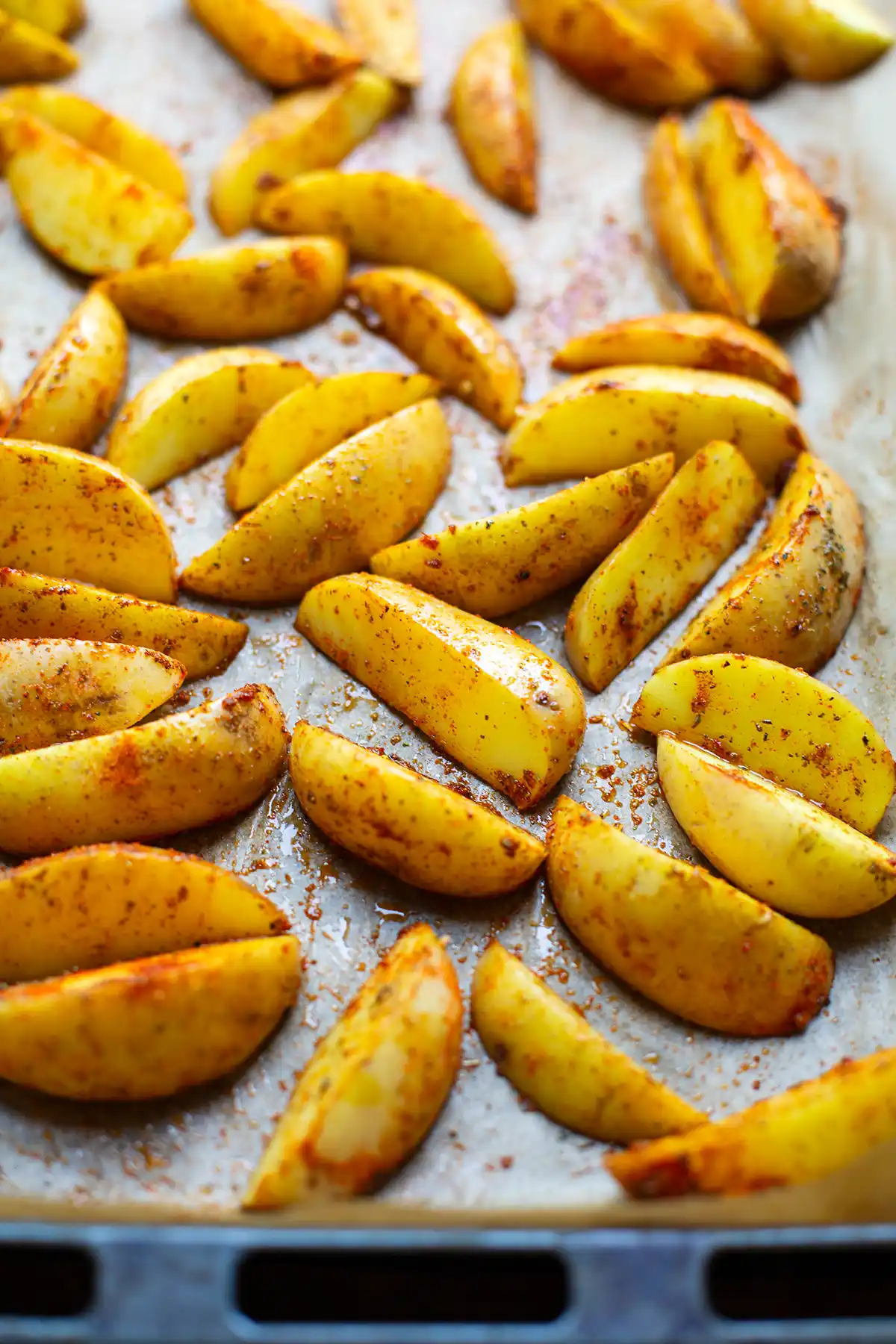 Die Kartoffelspalten gewürzt auf dem Backblech vor dem Backen im Ofen.