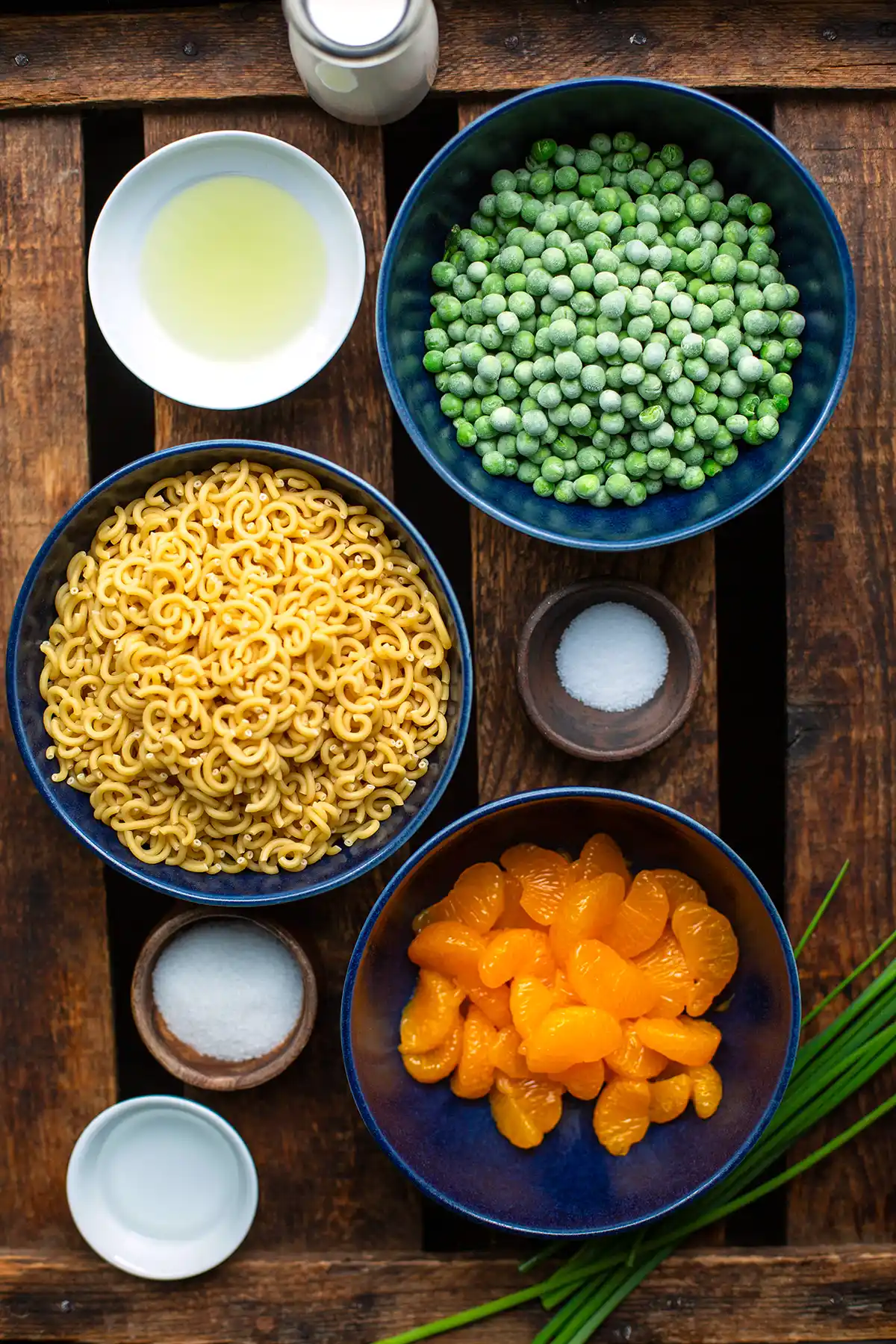 Zutaten: Mandarinen und Erbsen, darunter rohe Hörnchennudeln, Gewürze, Essig, Öl und Kaffeesahne