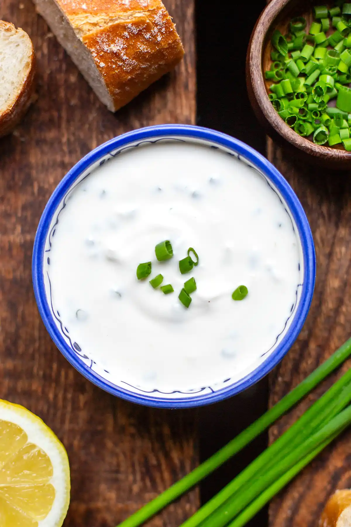 Eine blaue Schüssel mit selbstgemachter Sour Cream, garniert mit frischem Schnittlauch