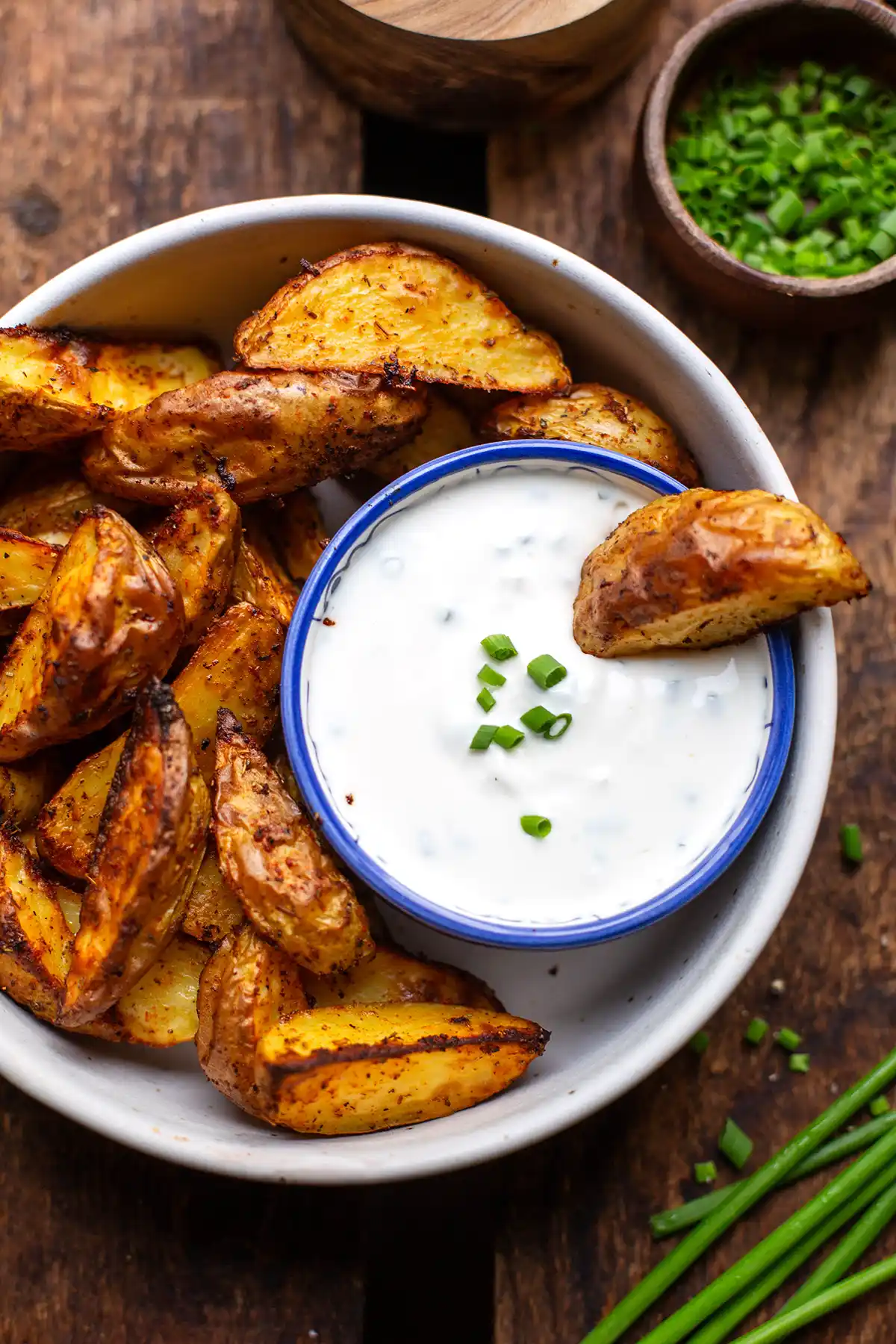 Fertige Sour Cream in einer Schale neben knusprigen Ofenkartoffeln vom Blech