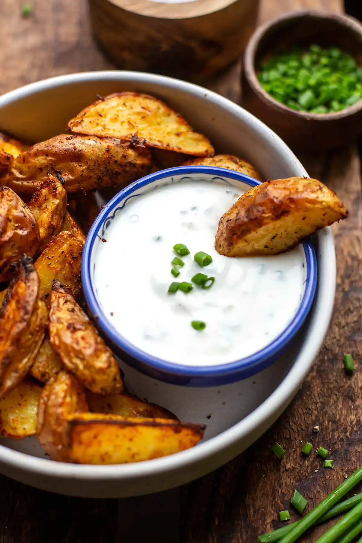 Sour Cream in einer Schale mit knusprigen Ofenkartoffeln, bestreut mit Schnittlauch