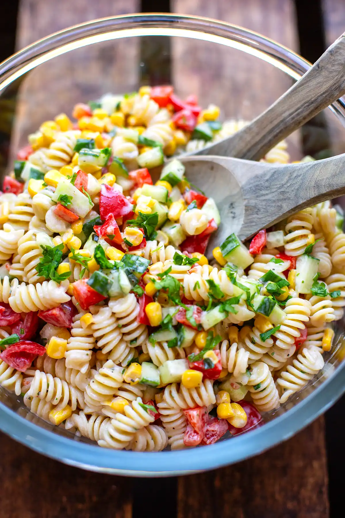 Frischer Nudelsalat mit Joghurt-Dressing, Cherrytomaten, Gurken, roter Paprika und Mais serviert in einer großen Schüssel