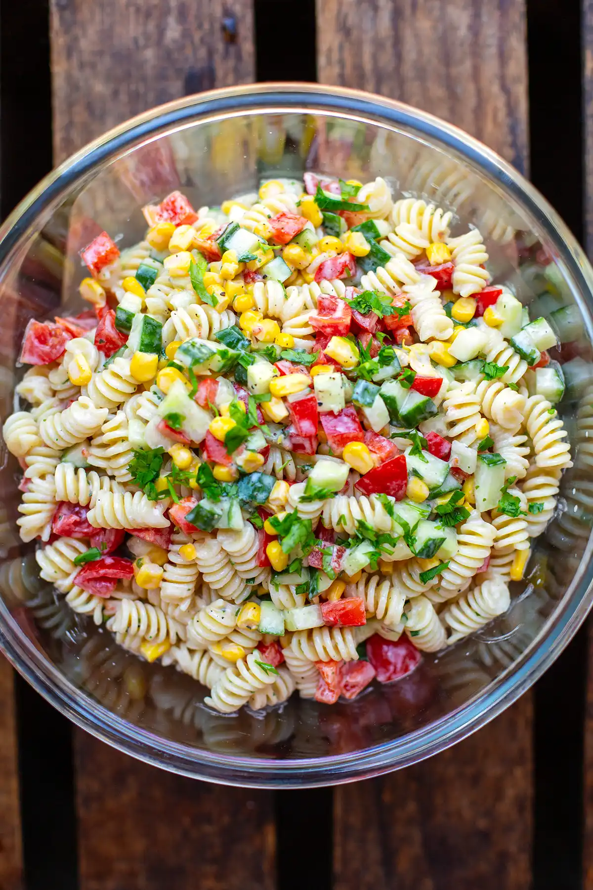 Fertig durchgezogener Nudelsalat mit Joghurt-Dressing und frischen Kräutern in einer Glasschüssel zum Servieren