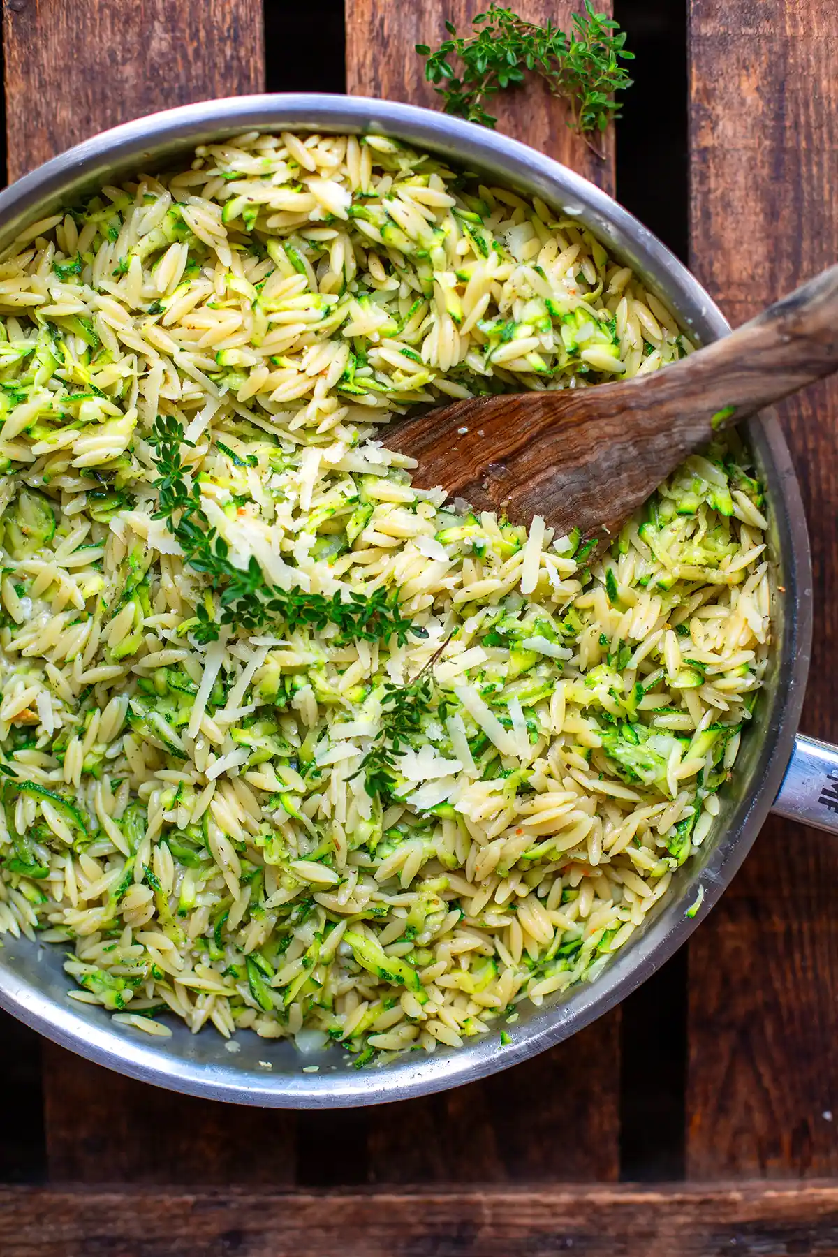 Cremiges One Pot Zucchini-Orzo mit geriebenem Parmesan serviert in einer Pfanne