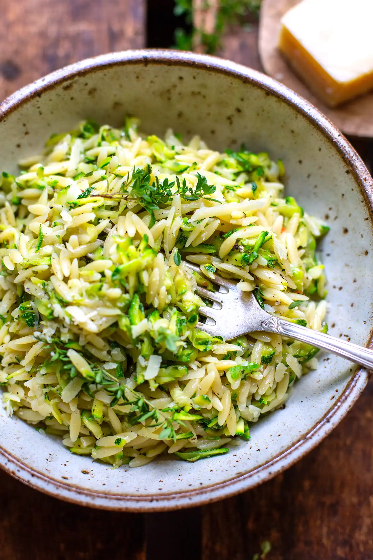 One Pot Zucchini-Orzo in einer rustikalen Keramikschüssel, die die feinen Zucchiniraspeln zeigt