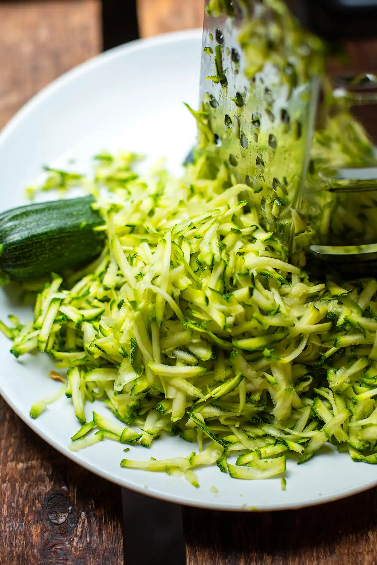 Geriebene Zucchini und Kastenreibe auf einem Teller für die Zucchini-Pasta