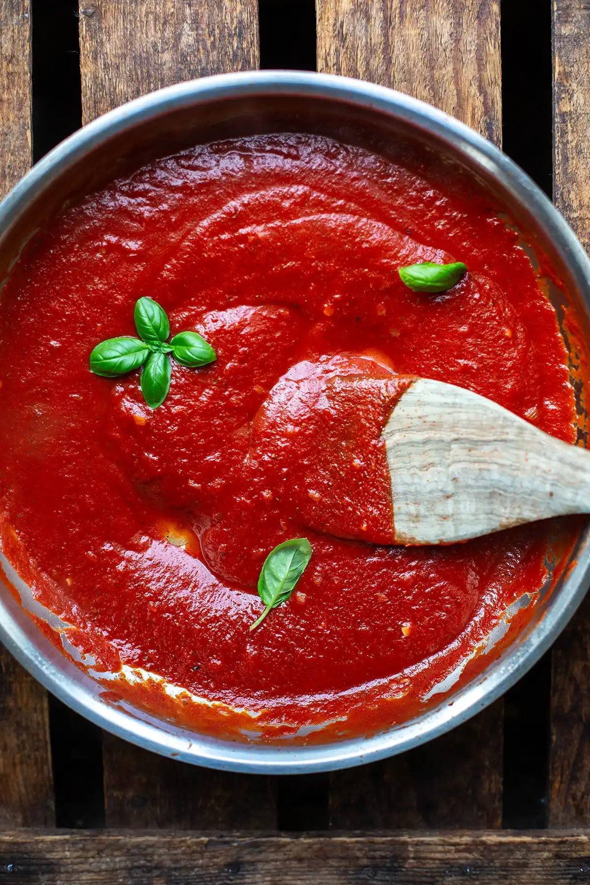 Sämige Napoli-Soße aus passierten Tomaten köchelt in einer großen Pfanne