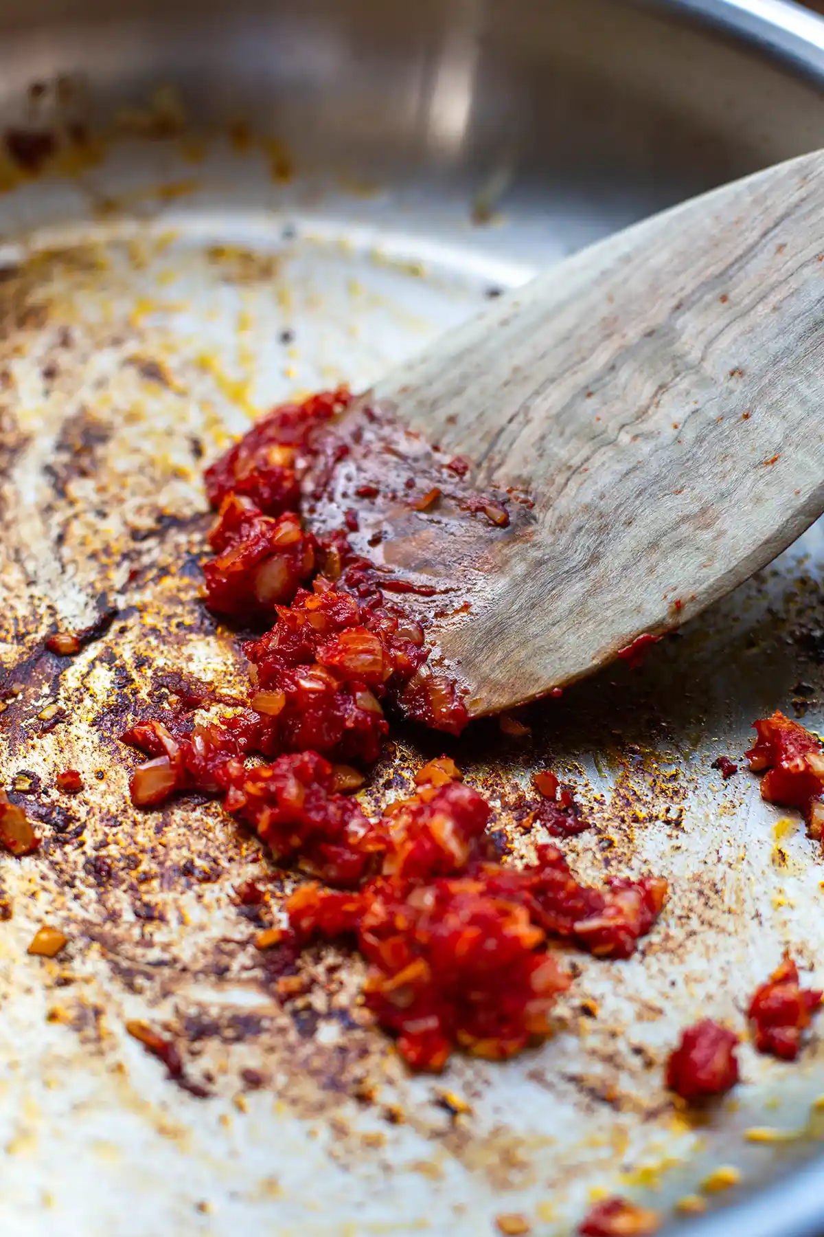 Tomatenmark wird mit Zwiebeln und Knoblauch in der Pfanne angeröstet
