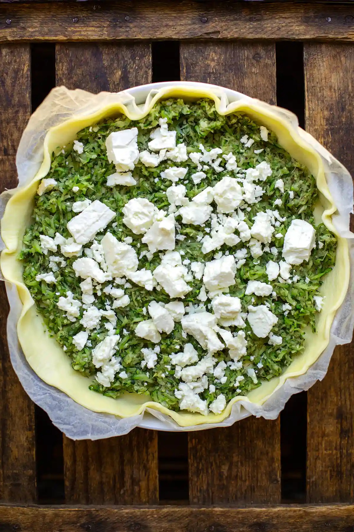 Gefüllte Zucchini-Quiche mit Fetakrümeln in der Form vor dem Backen