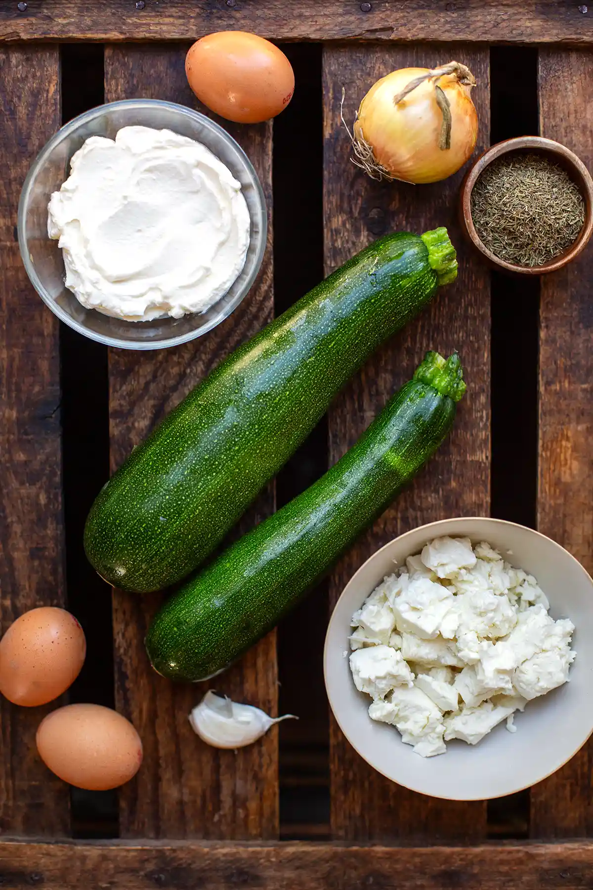 Zutaten für die vegetarische Zucchini-Quiche: Zucchini, Eier, Schmand, Feta, Pinienkerne, Zwiebel und Thymian