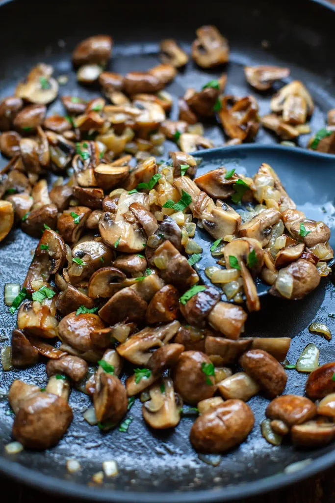Gebratene Champignons mit Zwiebeln und Petersilie in einer Pfanne