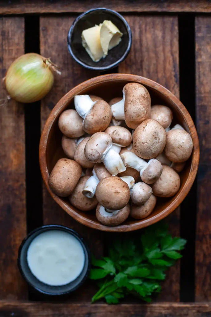 Zutaten für die Pilzpfanne mit Sahne: braune Champignons, Zwiebel, Butter, Sahne und Petersilie